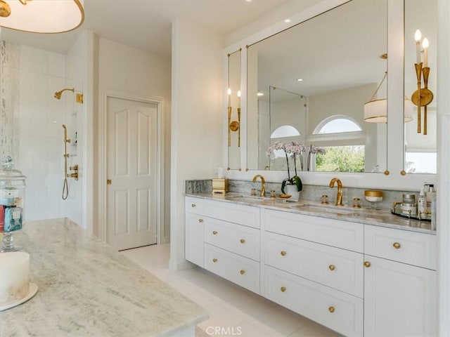 bathroom featuring double vanity, a sink, and a tile shower