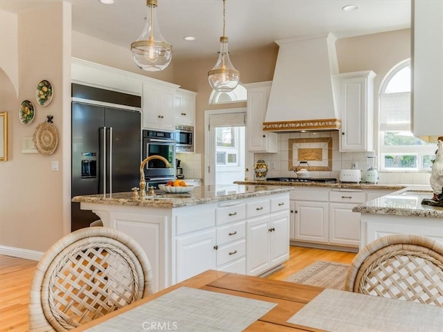 kitchen with light wood-style floors, decorative backsplash, custom range hood, and white cabinets