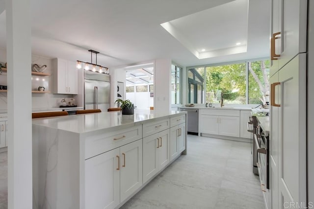 kitchen featuring a healthy amount of sunlight, white cabinets, a kitchen island, and stainless steel appliances