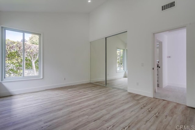 unfurnished bedroom featuring visible vents, multiple windows, wood finished floors, and a closet