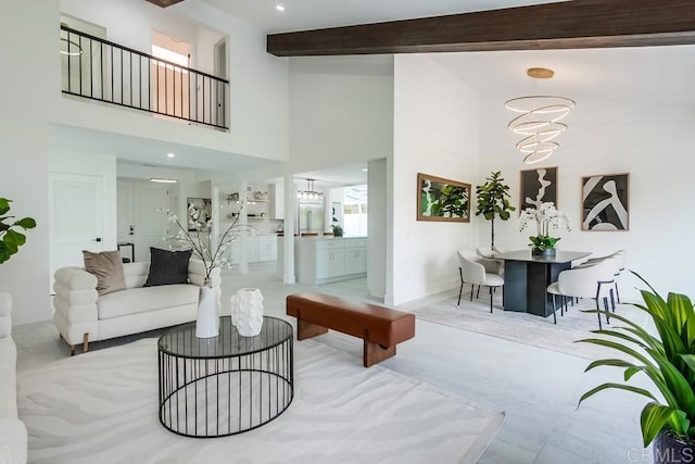 living room with baseboards, a notable chandelier, beam ceiling, and a towering ceiling
