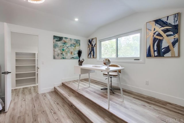 office area featuring baseboards, light wood-type flooring, and lofted ceiling