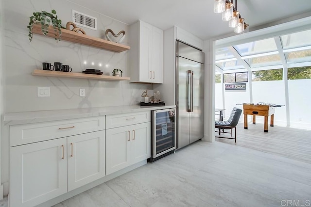 bar with built in refrigerator, visible vents, a bar, and wine cooler