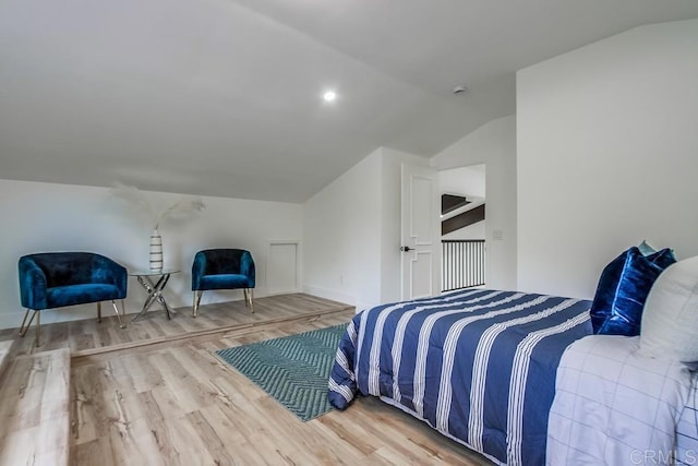 bedroom featuring baseboards, wood finished floors, and vaulted ceiling