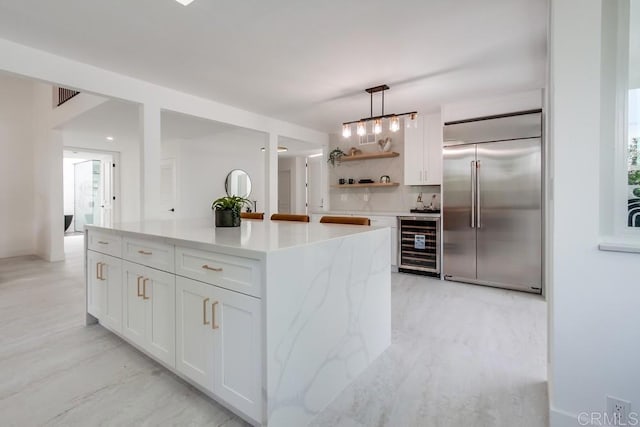 kitchen featuring open shelves, beverage cooler, white cabinetry, decorative light fixtures, and stainless steel built in refrigerator