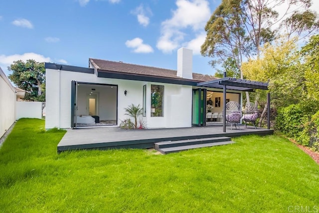 back of property with a chimney, a deck, a yard, a pergola, and stucco siding