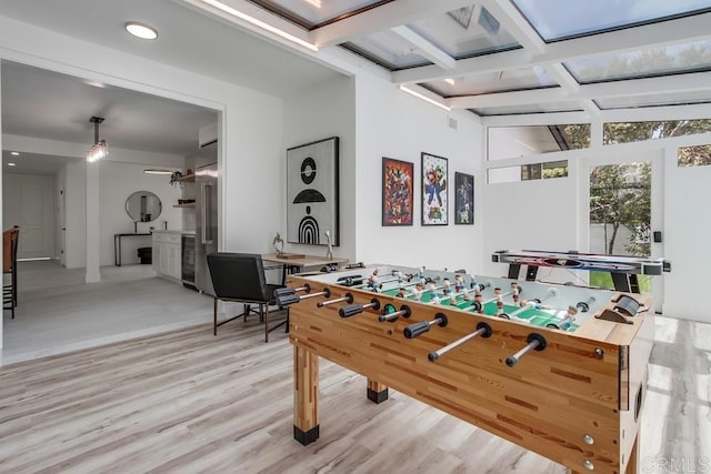 game room featuring light wood-type flooring, beam ceiling, beverage cooler, coffered ceiling, and recessed lighting