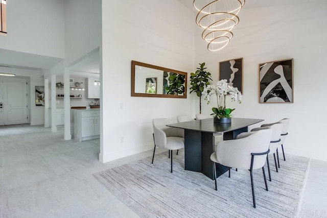 dining space with baseboards, a high ceiling, and an inviting chandelier