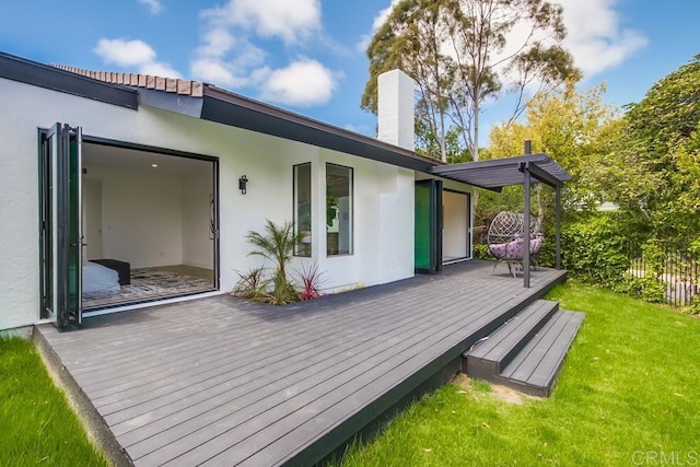 back of house featuring fence, a wooden deck, stucco siding, a chimney, and a yard