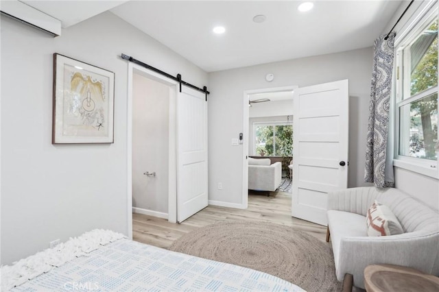 bedroom with recessed lighting, baseboards, a barn door, and light wood-style floors