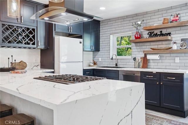 kitchen with island exhaust hood, dishwasher, a sink, freestanding refrigerator, and a peninsula