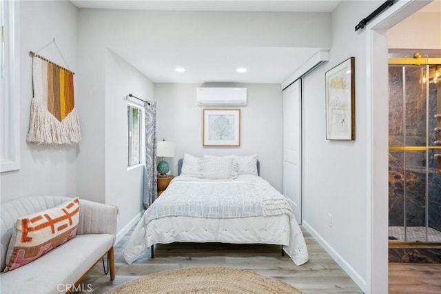 bedroom featuring a closet, wood finished floors, recessed lighting, a barn door, and a wall mounted AC