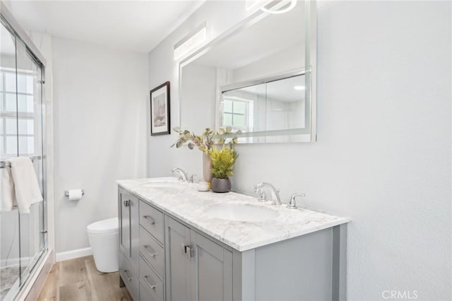 full bath featuring a sink, a stall shower, toilet, and wood finished floors