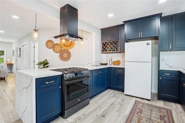 kitchen with freestanding refrigerator, light stone countertops, island range hood, stainless steel gas range, and light wood finished floors