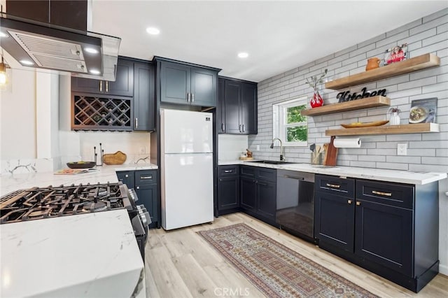 kitchen featuring tasteful backsplash, dishwasher, a sink, freestanding refrigerator, and light wood-style floors