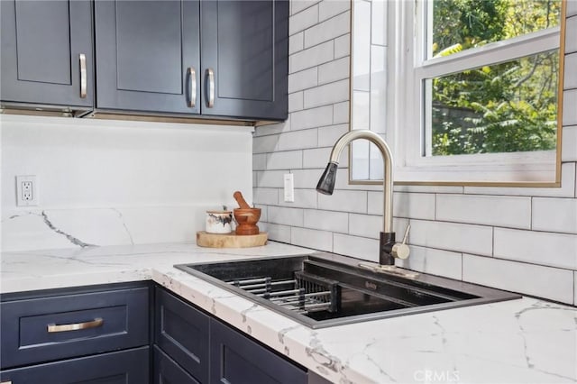 kitchen with a sink, light stone countertops, and backsplash