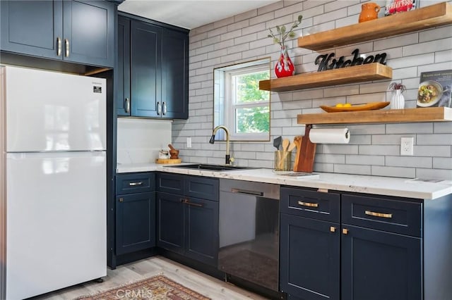 kitchen featuring decorative backsplash, open shelves, dishwasher, a sink, and freestanding refrigerator