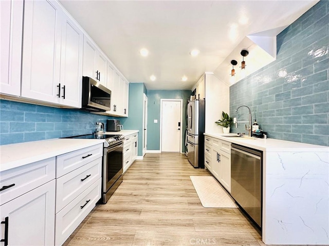 kitchen with white cabinets, a sink, stainless steel appliances, recessed lighting, and tasteful backsplash