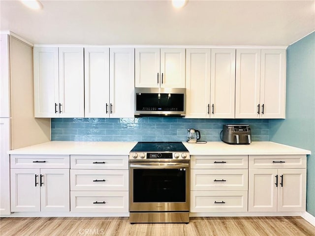 kitchen featuring light countertops, decorative backsplash, stainless steel appliances, and light wood finished floors