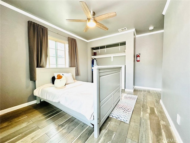 bedroom with visible vents, crown molding, baseboards, ceiling fan, and light wood-type flooring