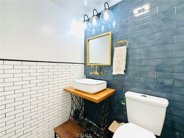 bathroom featuring a sink, toilet, and tile walls