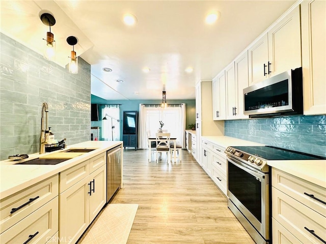 kitchen featuring light wood-style floors, light countertops, tasteful backsplash, a sink, and stainless steel appliances