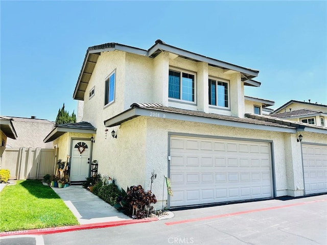 view of front of house featuring an attached garage, fence, and stucco siding