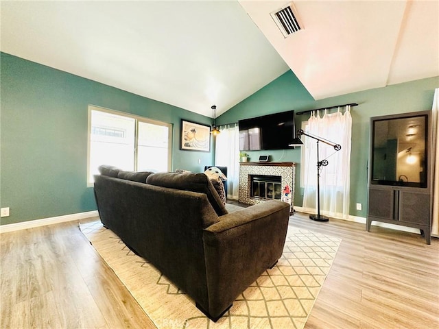 living area featuring visible vents, baseboards, vaulted ceiling, and light wood-type flooring