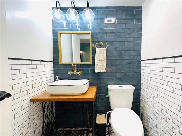 bathroom with toilet, tile walls, and a sink