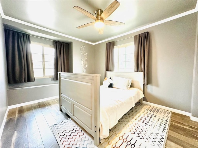 bedroom with baseboards, multiple windows, ornamental molding, and light wood-style flooring
