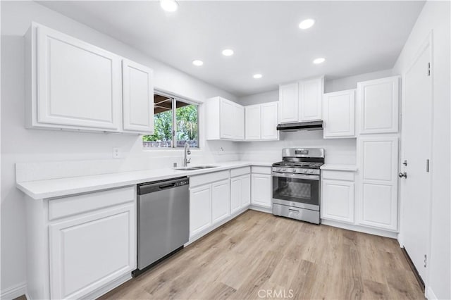 kitchen with recessed lighting, under cabinet range hood, white cabinets, a sink, and appliances with stainless steel finishes