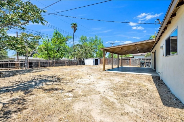 view of yard with a fenced backyard, a patio area, a shed, and an outbuilding