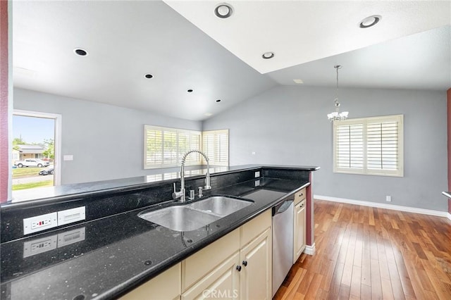 kitchen featuring stainless steel dishwasher, lofted ceiling, cream cabinetry, a sink, and light wood finished floors