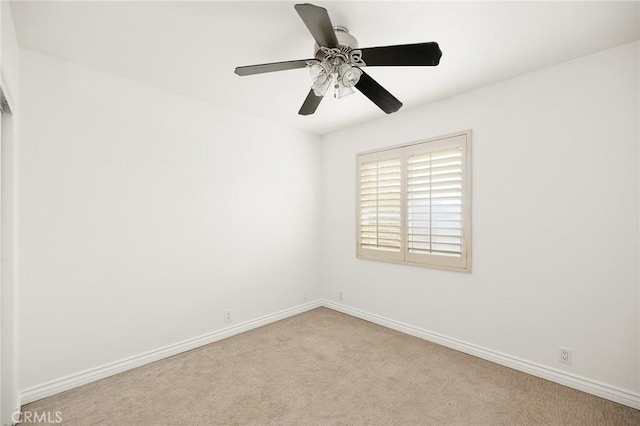 unfurnished room with a ceiling fan, baseboards, and carpet