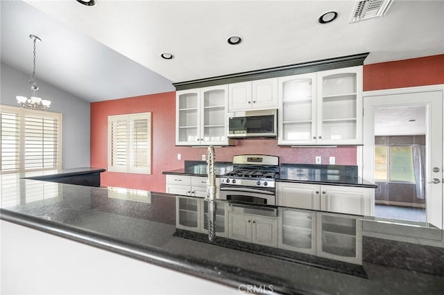 kitchen with a notable chandelier, visible vents, stainless steel appliances, white cabinetry, and vaulted ceiling