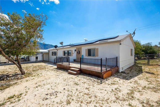 12859 Danbury St, Whitewater, CA 92282 - rear view of house featuring roof mounted solar panels, fence, and a deck with mountain view