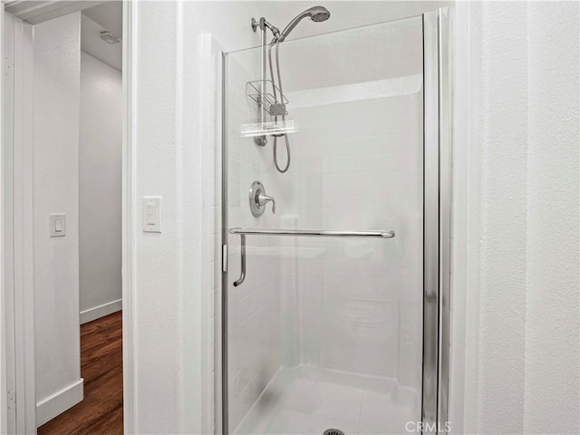 full bathroom featuring baseboards, a shower stall, and wood finished floors