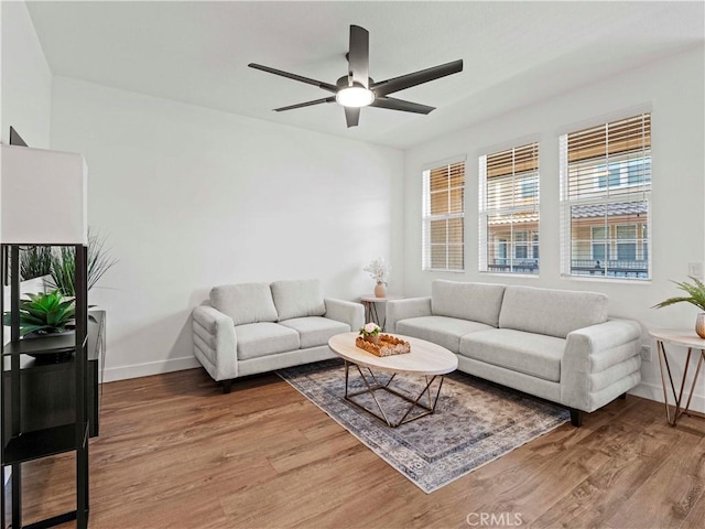 living area featuring baseboards, a ceiling fan, and light wood-style flooring