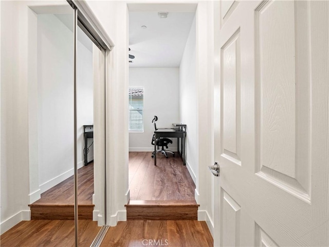 corridor featuring baseboards and wood finished floors