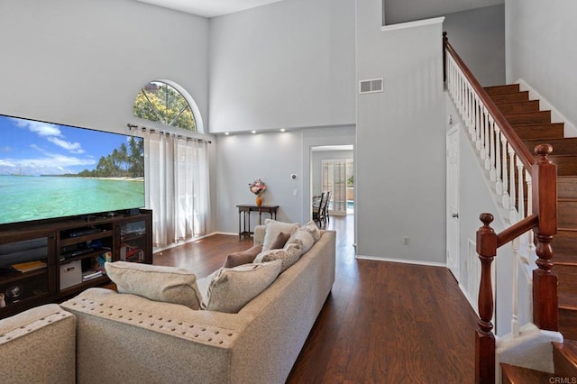 living room with stairway, a towering ceiling, wood finished floors, and visible vents