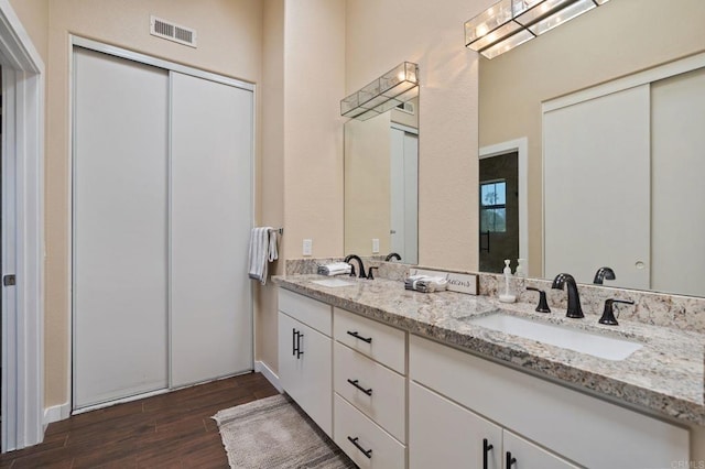 full bathroom featuring a sink, double vanity, wood finished floors, and visible vents