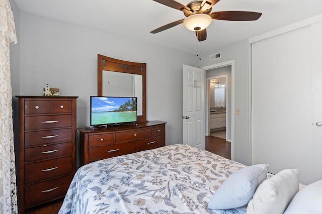 bedroom with a ceiling fan, visible vents, dark wood finished floors, and a closet