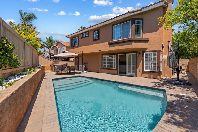 rear view of house featuring a gazebo, a fenced backyard, stucco siding, and a fenced in pool