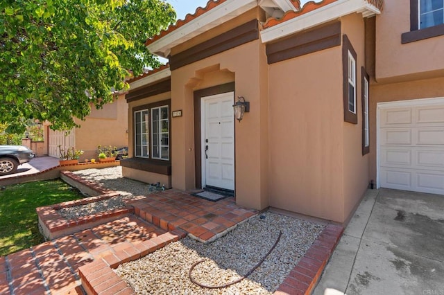 property entrance with a garage, stucco siding, and a tile roof