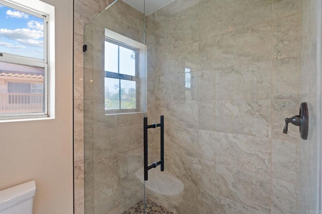 full bath featuring a healthy amount of sunlight, toilet, and tiled shower