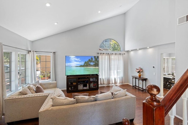 living area featuring high vaulted ceiling, visible vents, plenty of natural light, and wood finished floors