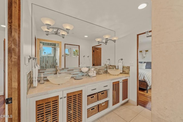 ensuite bathroom with double vanity, a sink, decorative backsplash, and tile patterned flooring