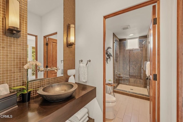 bathroom featuring visible vents, tasteful backsplash, toilet, and a shower stall