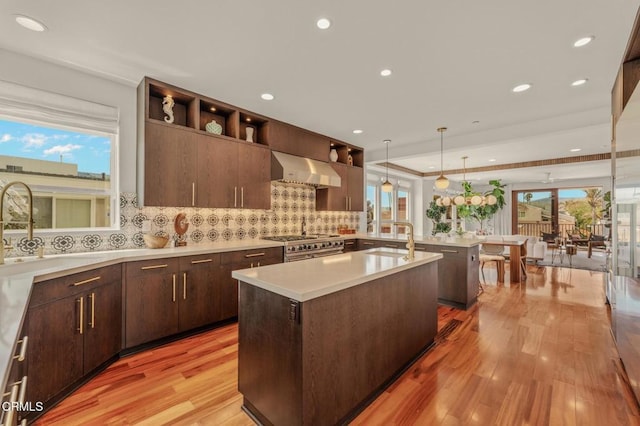 kitchen featuring a sink, light countertops, open shelves, and wall chimney exhaust hood
