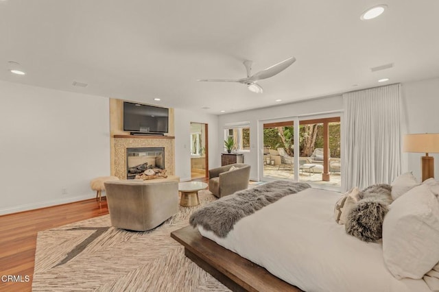 bedroom with a premium fireplace, access to exterior, recessed lighting, baseboards, and wood finished floors